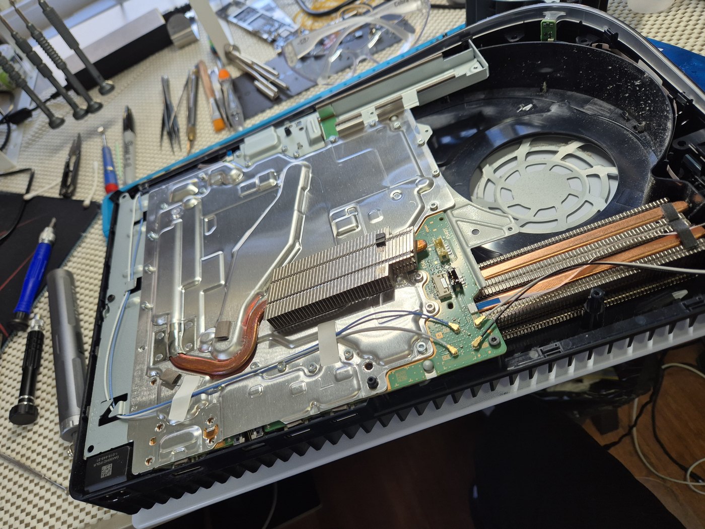 Game console opened with internal heat pipes and board visible