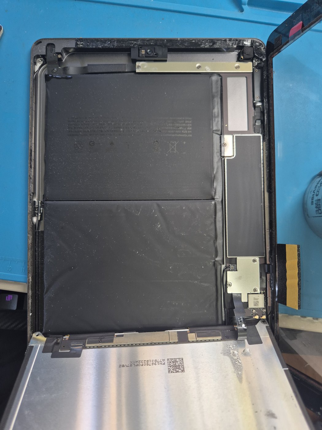 iPad opened with internal battery and frame visible during repair